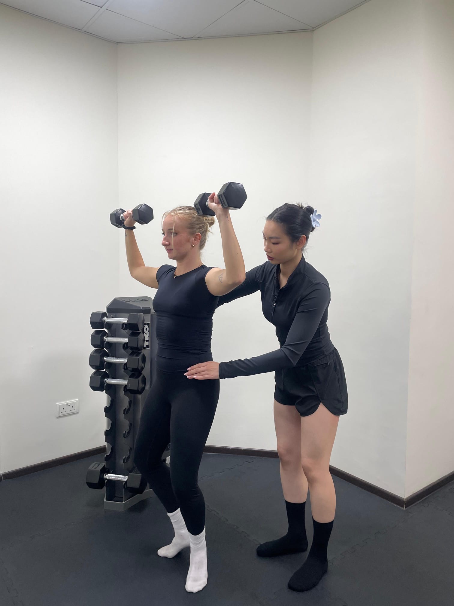 PTatHome personal trainer coaching a client through a dumbbell shoulder press